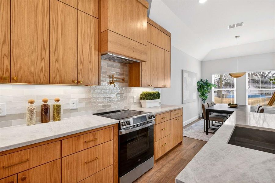 Kitchen featuring stainless steel range with electric stovetop, hanging light fixtures, light stone countertops, decorative backsplash, and dark wood-type flooring