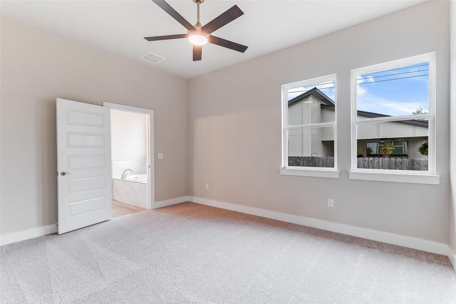 Empty room featuring light colored carpet and a ceiling fan
