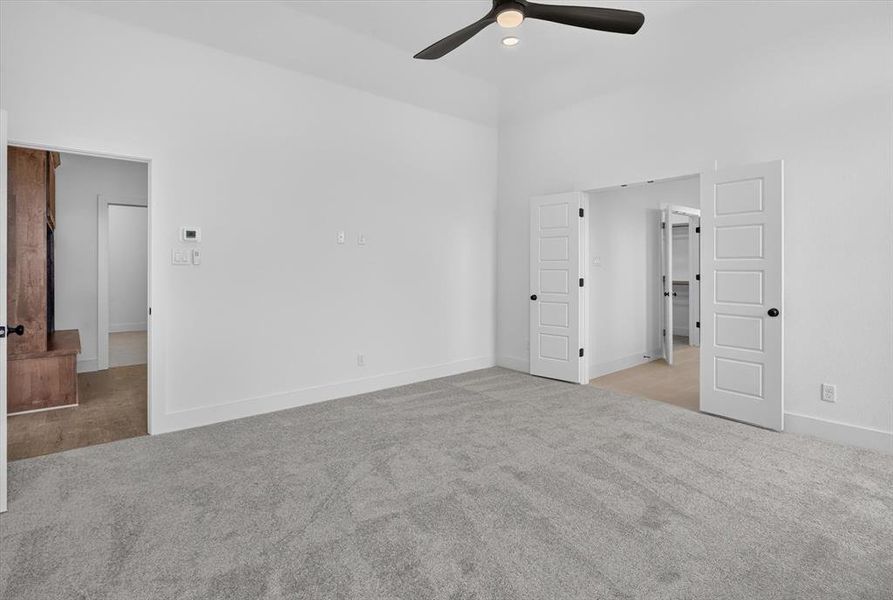 Spacious room featuring vaulted ceilings, light gray carpet flooring, a ceiling fan with integrated lighting, and white baseboards Spacious room featuring vaulted ceilings, light gray carpet flooring, a ceiling fan with integrated lighting, and white baseboards