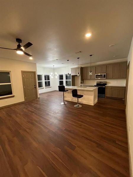 Kitchen with open floor plan, appliances with stainless steel finishes, hanging light fixtures, light countertops, and a ceiling fan Kitchen with open floor plan, appliances with stainless steel finishes, hanging light fixtures, light countertops, and a ceiling fan