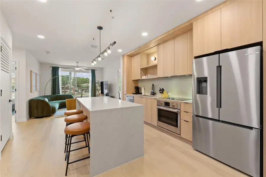 Sleek modern cabinetry and a waterfall-edge island anchor this open-concept kitchen space. Sleek modern cabinetry and a waterfall-edge island anchor this open-concept kitchen space.