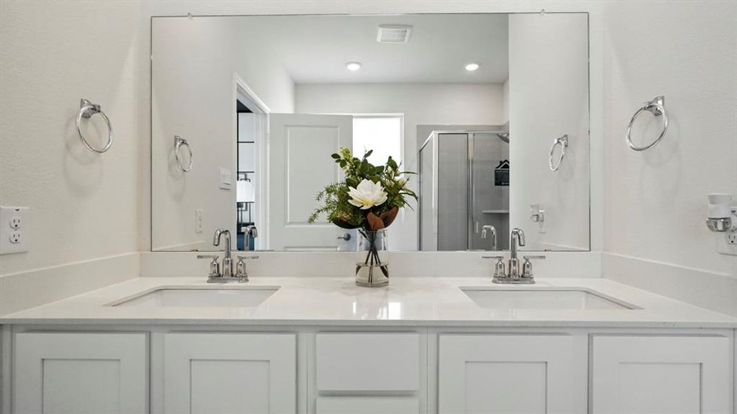 White vanity with dual integrated sinks and polished chrome fixtures, featuring a full-width mirror and recessed lighting