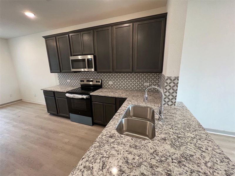 Kitchen with stainless steel appliances, tasteful backsplash, light stone counters, and recessed lighting Kitchen with stainless steel appliances, tasteful backsplash, light stone counters, and recessed lighting