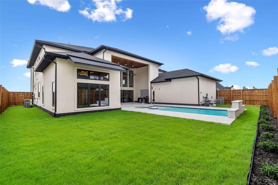 Rear view of house with central AC, a fenced in pool, and a lawn