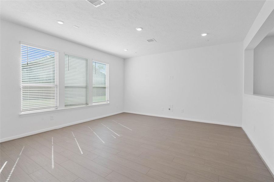 Bring family and friends together in this beautiful family room! It features high ceilings, recessed lighting, custom paint, stunning flooring, and large windows that fill the space with natural light all day long.