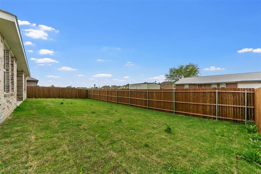 Expansive backyard featuring a full perimeter privacy fence with wood panels and metal posts