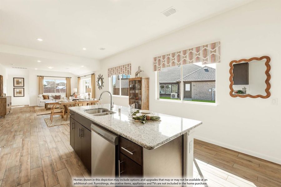 Kitchen island with granite countertop and sink, open to dining and living area with wood-look floors