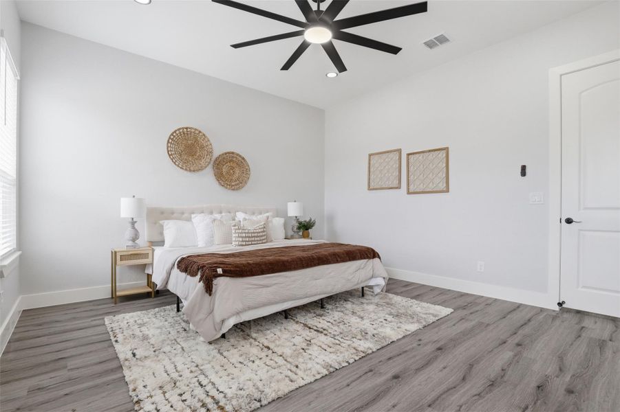 Spacious room featuring wood-finish flooring, a contemporary ceiling fan with integrated lighting, recessed lighting, and a white paneled door with matte black hardware