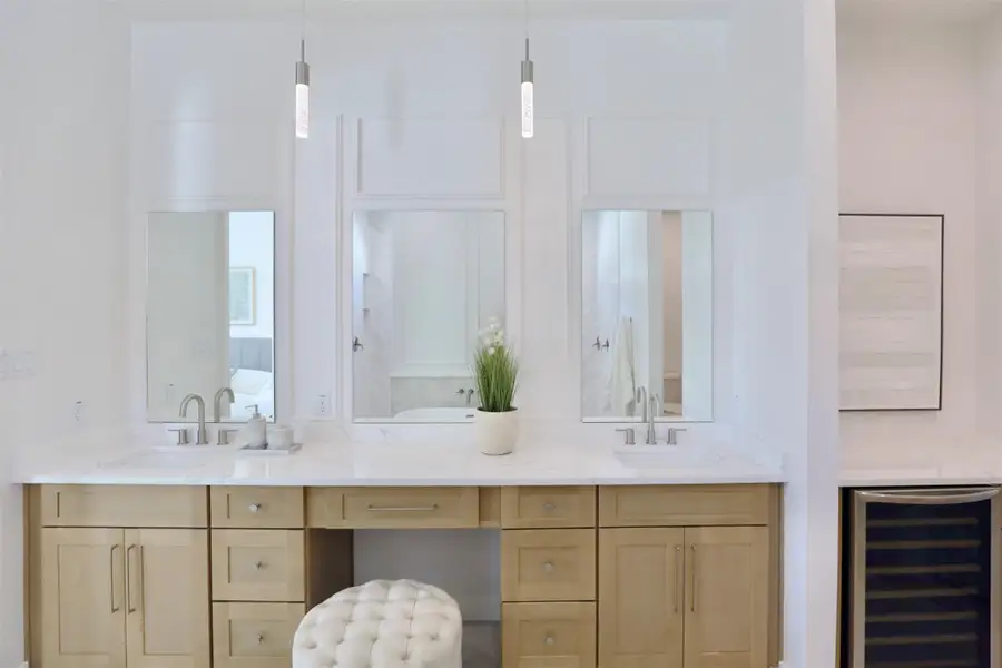 The primary ensuite is captivating with its refined design, featuring a statement vanity, intricate wall details, and a 24" wine and beverage fridge.