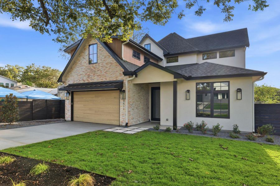 View of front of house with a garage, stucco siding, concrete driveway, and brick siding