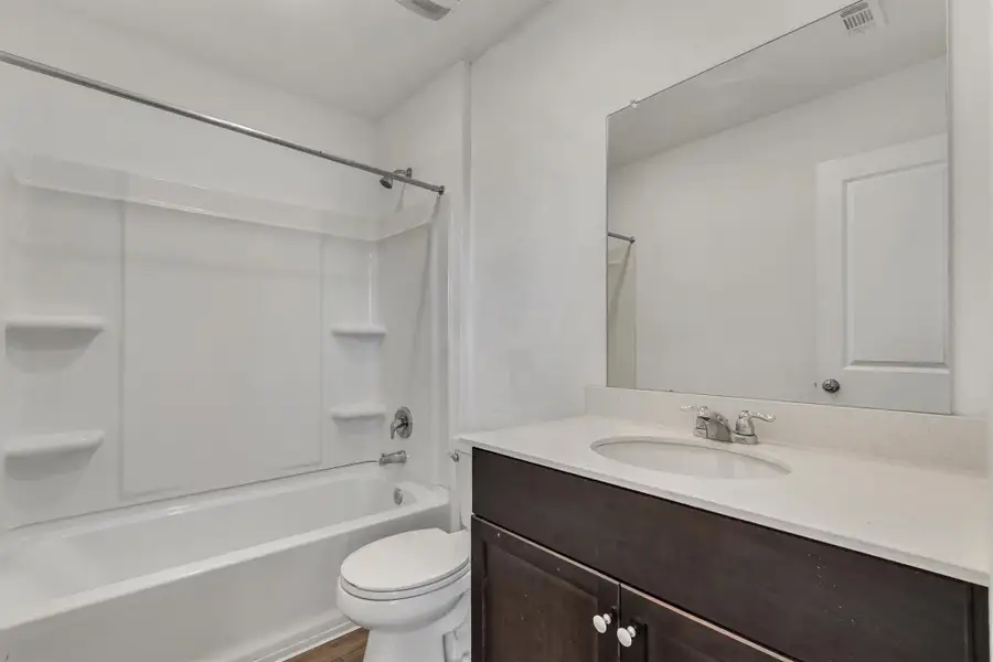 A classic tub and shower combination sits adjacent to a dark vanity. A classic tub and shower combination sits adjacent to a dark vanity.