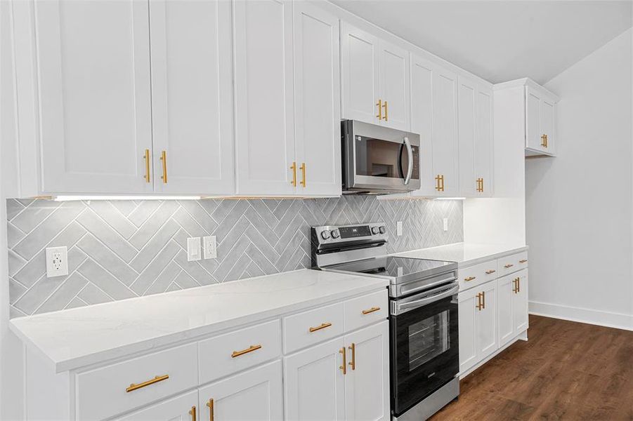 Kitchen featuring baseboards, decorative backsplash, dark wood-style floors, white cabinets, and stainless steel appliances