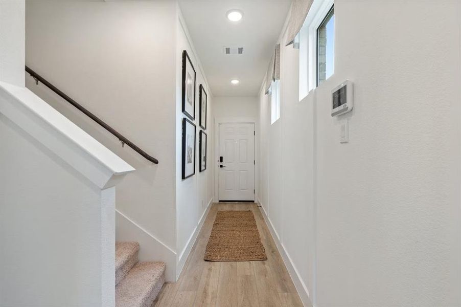 Hallway with light wood finished floors, stairway, recessed lighting, and baseboards