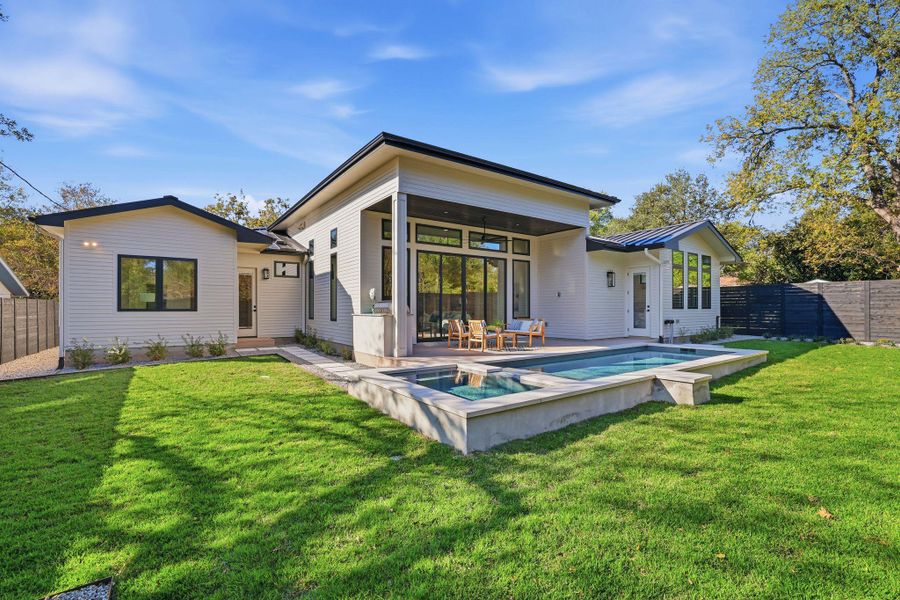 Rear view of property with a fenced backyard, a standing seam roof, a metal roof, and a patio area