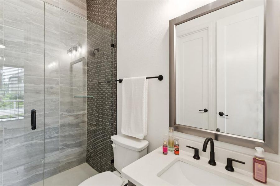 Bathroom featuring vanity, toilet, and a shower with door