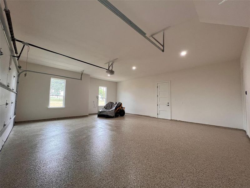 Spacious garage featuring a speckled epoxy floor, recessed lighting, and white interior walls