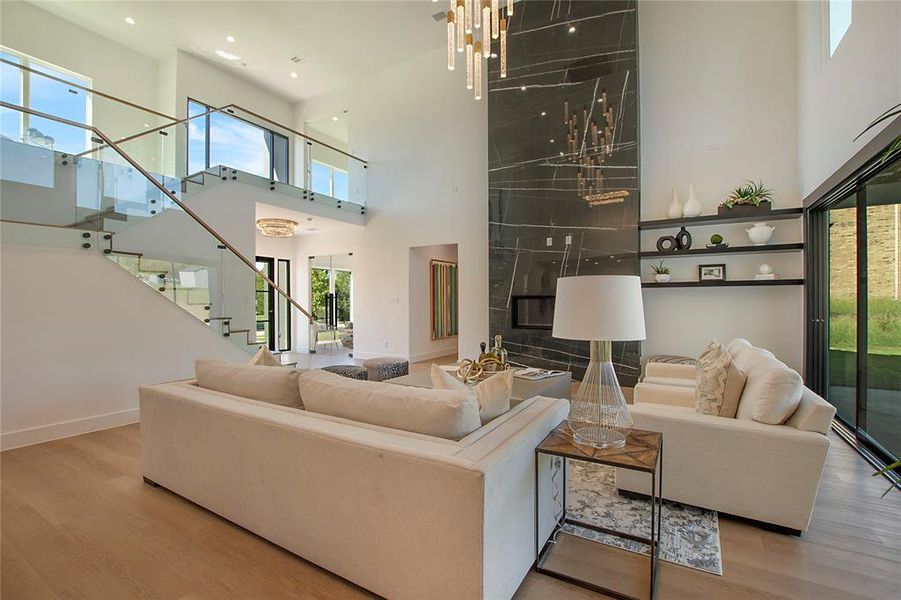 Living room featuring light hardwood / wood-style floors, a high ceiling, and a chandelier