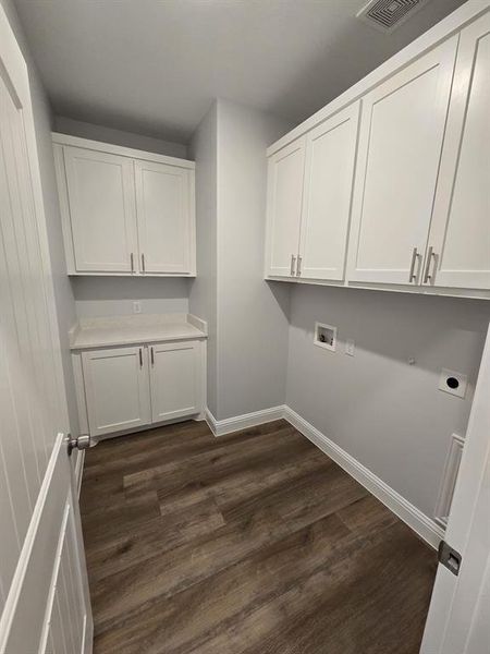 Washroom with hookup for an electric dryer, washer hookup, dark hardwood / wood-style floors, and cabinets