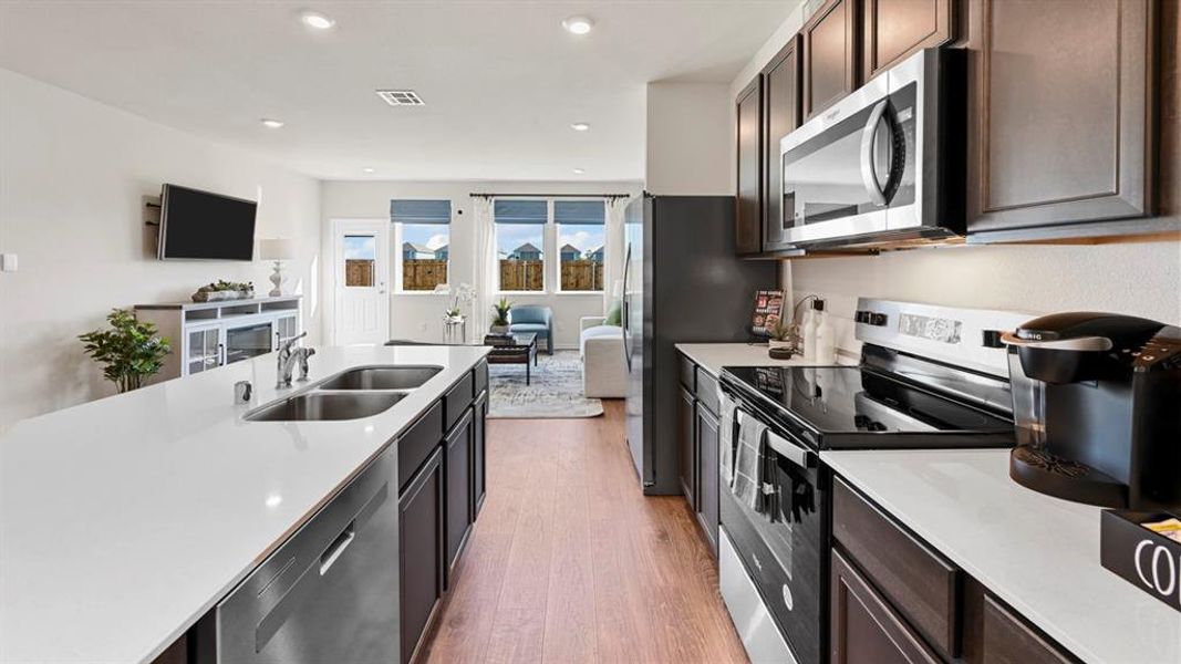 Kitchen featuring appliances with stainless steel finishes, light wood-type flooring, open floor plan, light stone countertops, and recessed lighting