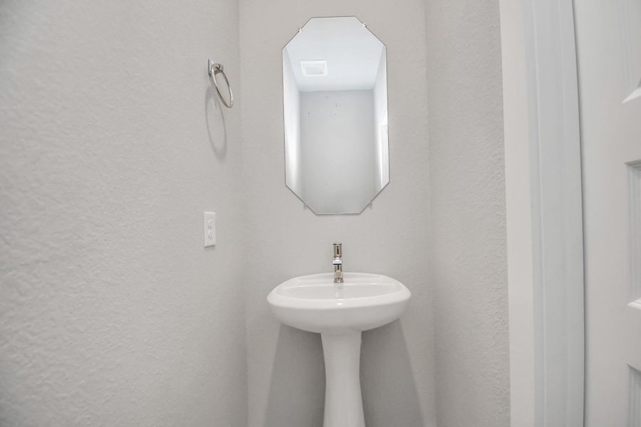 Sophisticated half bathroom adorned with contemporary finishes. The elegant 5-panel door welcomes you to a space where style meets functionality. Notice the sleek hardware accents that add a touch of modern charm. Sample photo of completed home with similar floor plan. Actual colors and selections may vary.