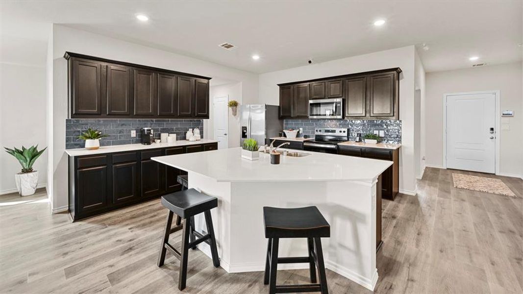 Well-appointed kitchen featuring dark wood cabinetry, white countertops, and a tiled backsplash