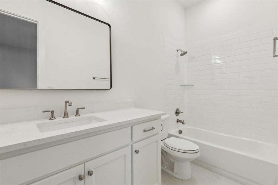 Full bathroom featuring tiled shower / bath combo, vanity, tile patterned floors, and toilet