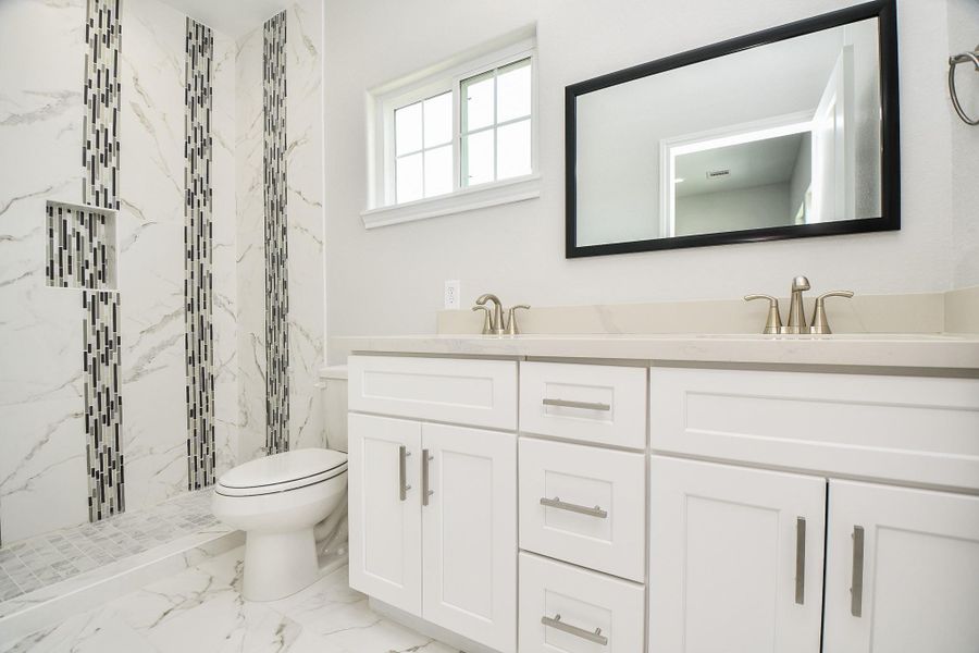 Discover luxury in this master bathroom featuring a sleek double vanity with custom cabinetry and a stunningly tiled shower.