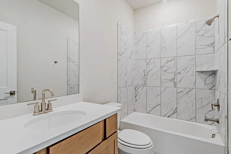 The third full bathroom continues the home's elegant aesthetic, with polished tilework, a wide mirror, and a modern vanity. The third full bathroom continues the home's elegant aesthetic, with polished tilework, a wide mirror, and a modern vanity.