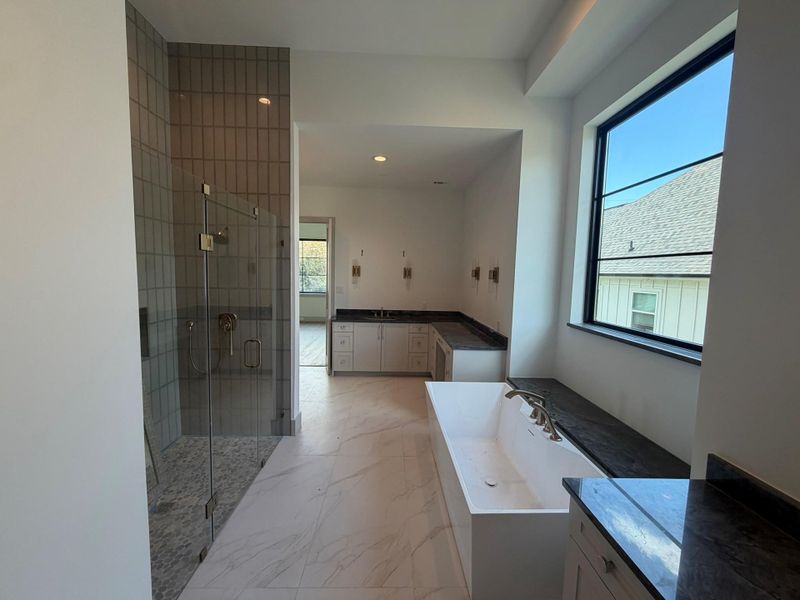 The primary bath featuring the spacious walk-in shower refined tile surrounding and luxurious vessel tub. This progress photo was taken August 11.