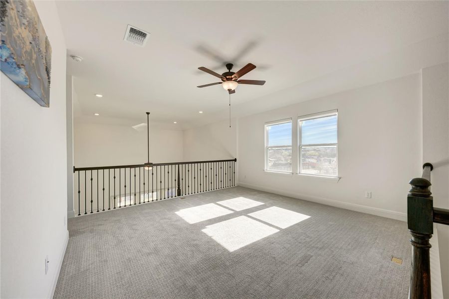 Carpeted loft space featuring dual windows, recessed lighting, and a ceiling fan