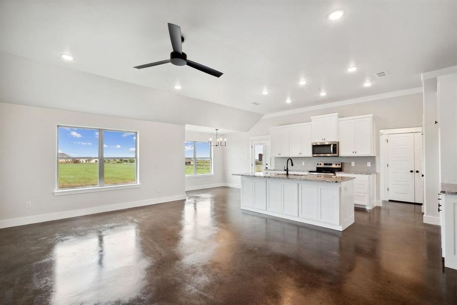 Kitchen with white cabinetry, tasteful backsplash, light stone counters, a kitchen island with sink, and stainless steel appliances