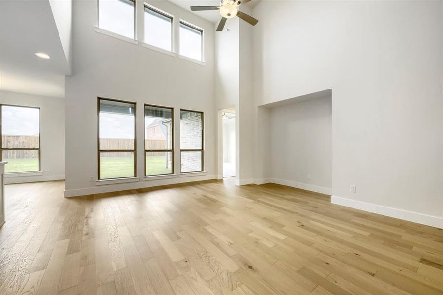 Expansive living area featuring soaring ceilings and wood-finish flooring Expansive living area featuring soaring ceilings and wood-finish flooring