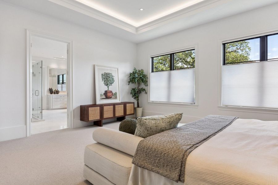 [Primary Bedroom]White oak floors transition to Berber-style wool carpet in the secluded primary suite. Amenities include a 10-ft tray ceiling, cove and recessed lighting, and pre-wiring for a wall-mount television and speakers.
