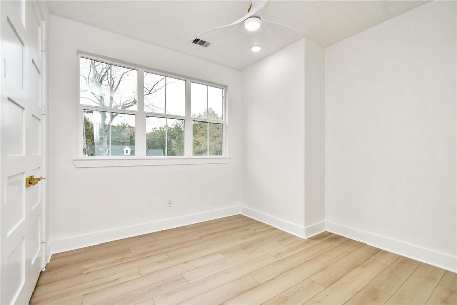 Thoughtfully designed bedroom featuring a large window that captures tranquil views of the wooded exterior. The combination of natural light and modern recessed fixtures keeps the space feeling open and airy.