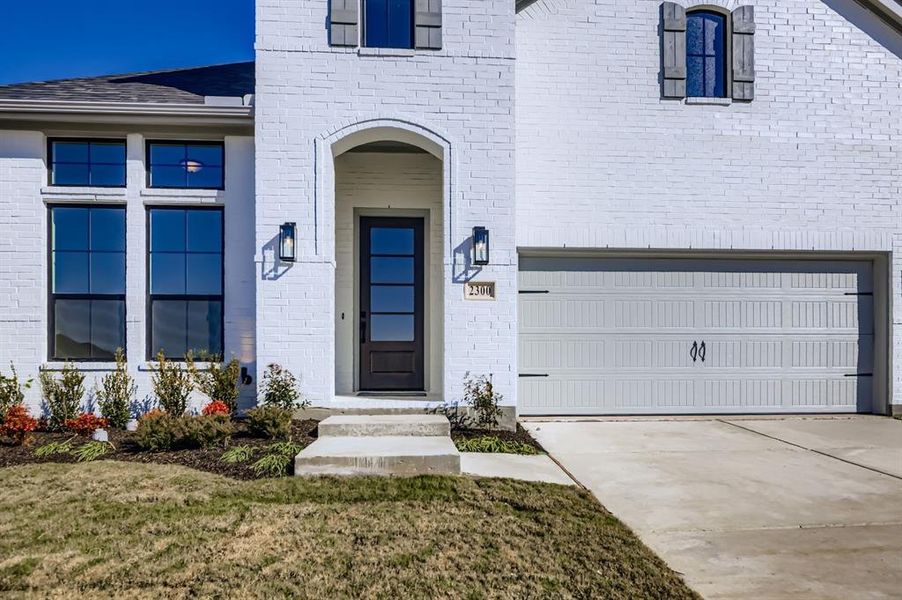Entrance to property featuring brick siding, driveway, and a yard