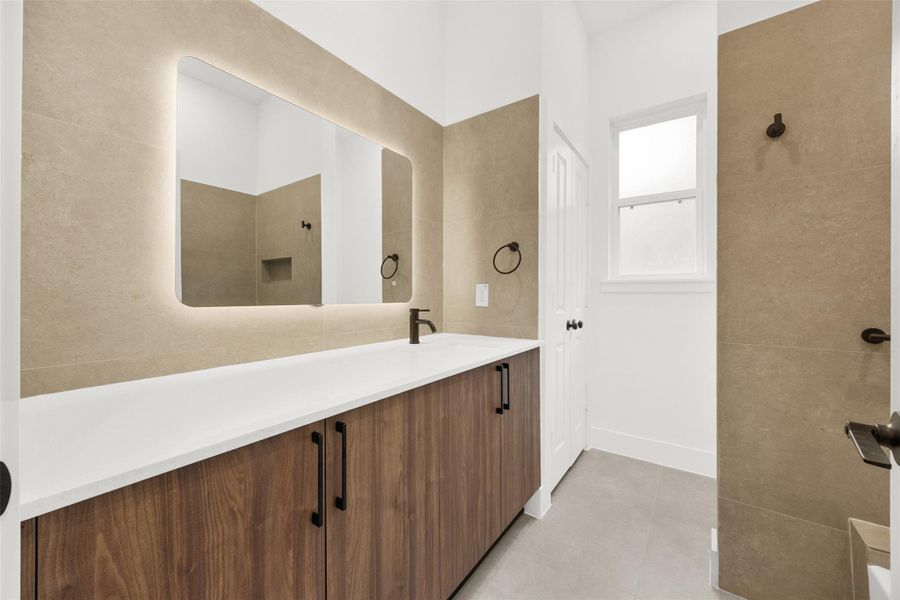 Stylish bathroom with vanity, quartz countertop, and illuminated mirror.