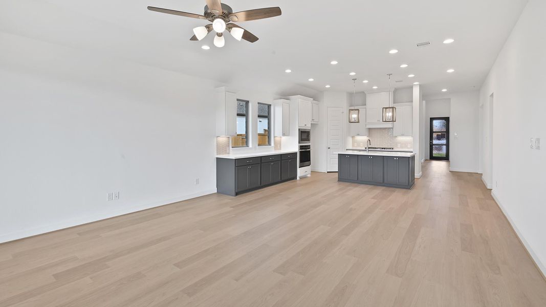 Kitchen featuring open floor plan, light countertops, recessed lighting, light wood-type flooring, and a center island with sink