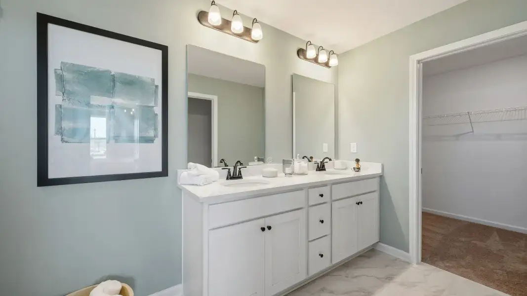 Modern primary bathroom with double vanity and convenient walk-in closet in Langley Overlook townhome in Loganville, GA