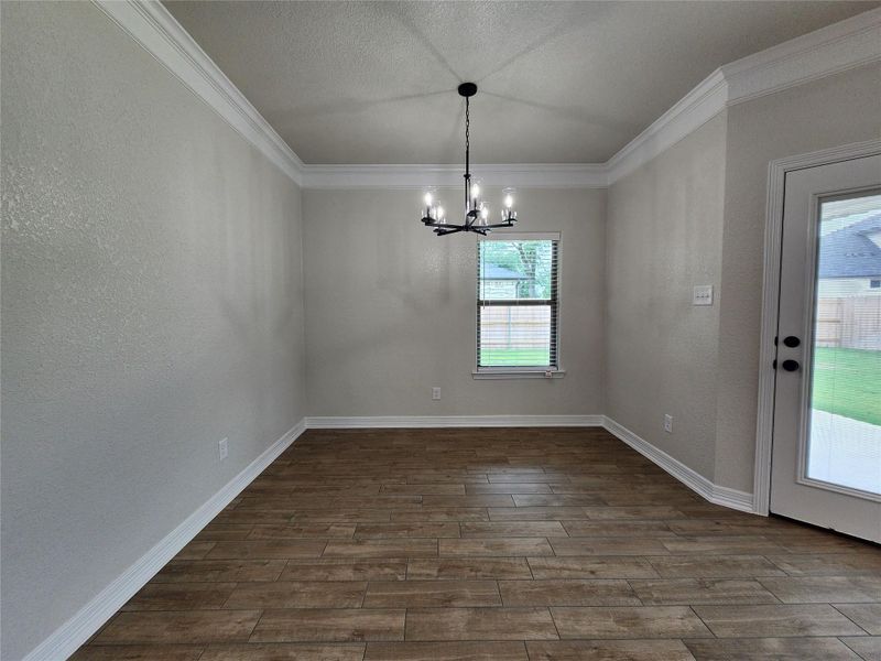 A refined dining space features crown molding, wood plank flooring, and a contemporary chandelier. A refined dining space features crown molding, wood plank flooring, and a contemporary chandelier.