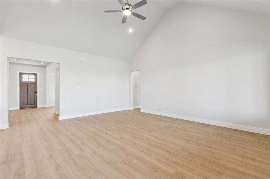 Empty room featuring high vaulted ceiling, light wood-style floors, recessed lighting, and ceiling fan
