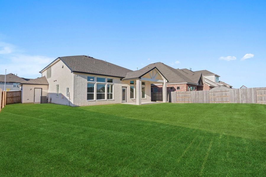 Another view of the large backyard highlights the spacious lawn and covered patio—perfect for weekend barbecues, morning coffee, or simply relaxing outdoors in your private retreat.
