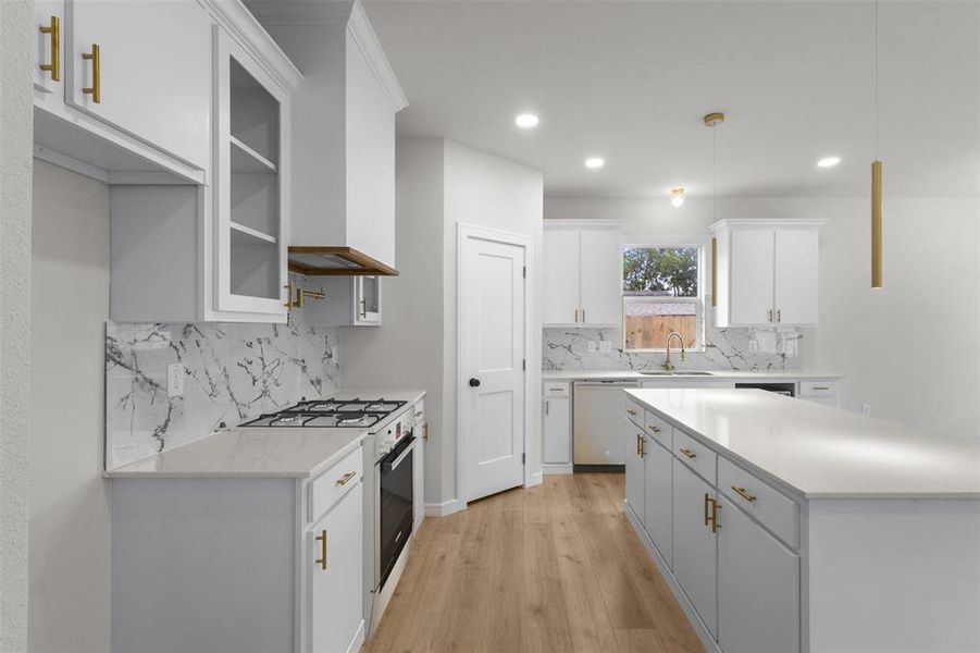 Contemporary kitchen featuring white cabinetry, light countertops, a patterned backsplash, wood-finish flooring, and a central island