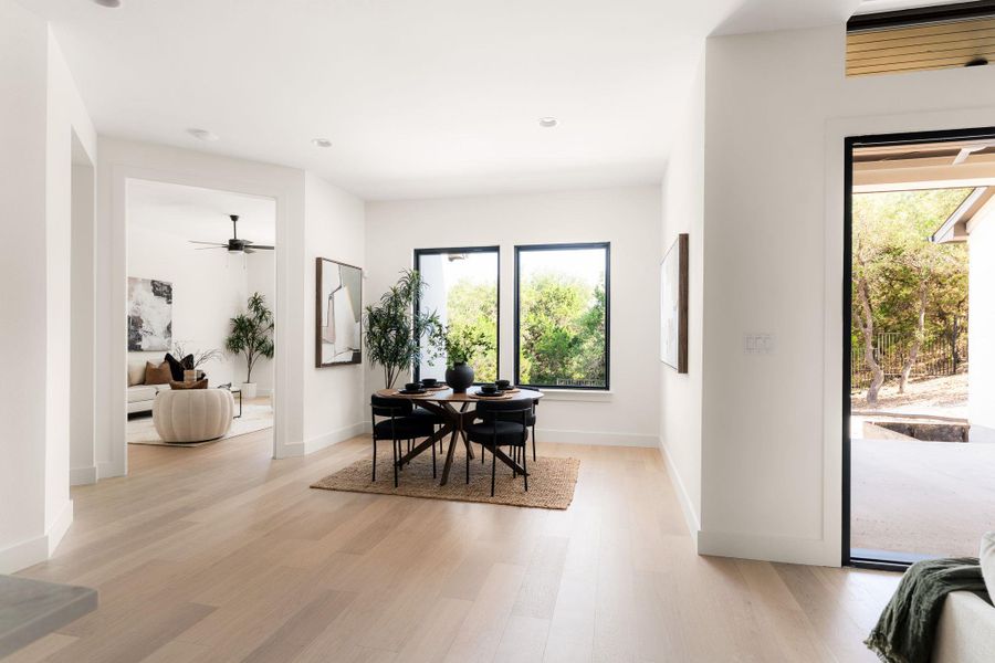 Naturally illuminated dining area features light hardwood floors and expansive views of the wooded surroundings.
