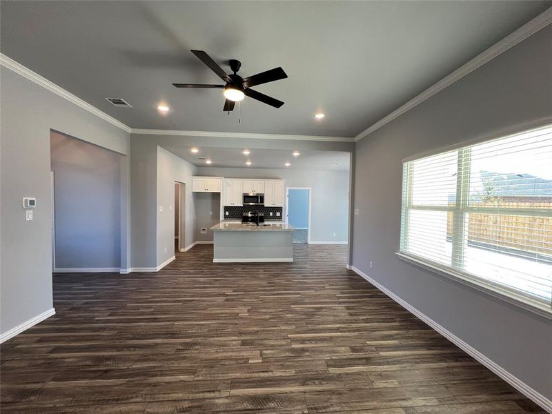 Unfurnished living room featuring ceiling fan, dark hardwood / wood-style flooring, and ornamental molding