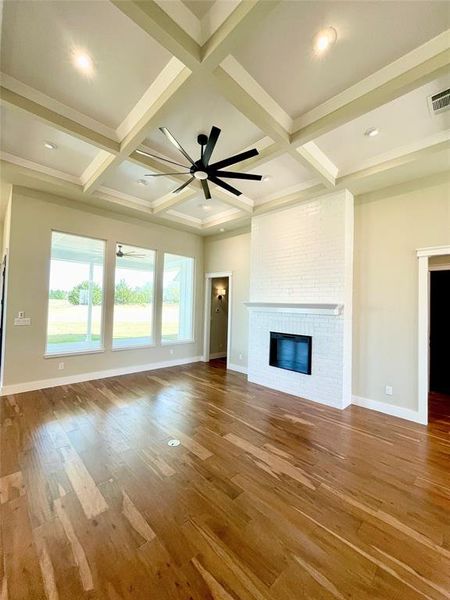 Unfurnished living room with a ceiling fan, a fireplace, coffered ceiling, and light wood-style flooring
