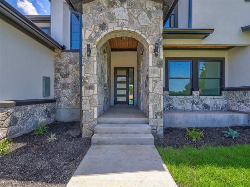 Natural stone masonry and a dramatic arched entryway create an impressive first impression.