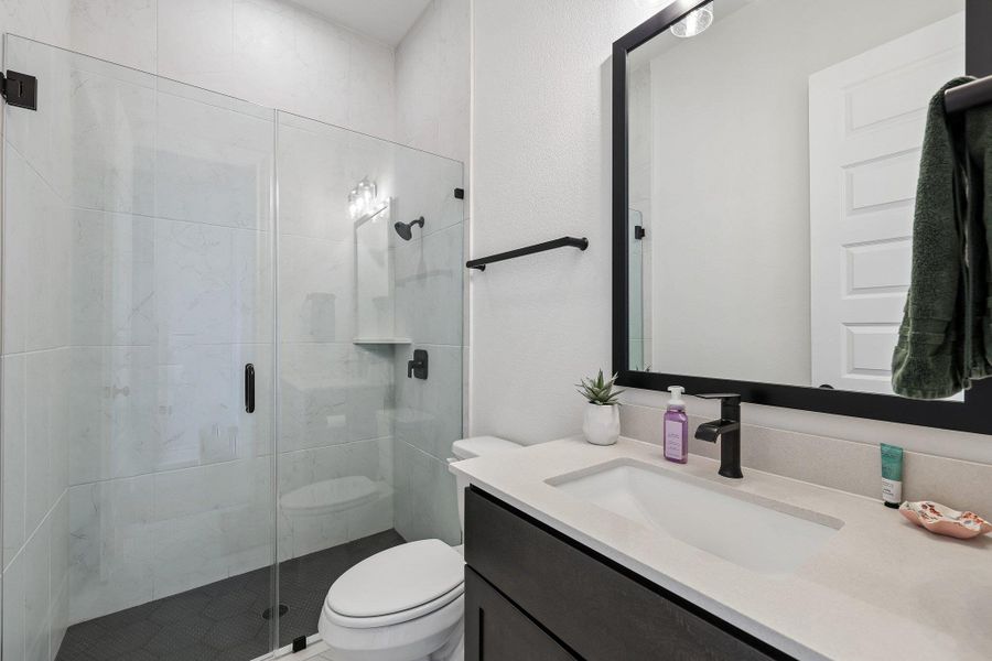 Contemporary bathroom featuring a frameless glass shower enclosure with white tiled walls and a dark tiled floor