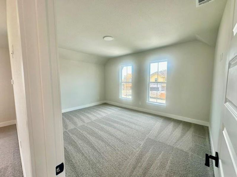 A spacious, naturally illuminated room boasts plush carpeting and multiple large windows. A spacious, naturally illuminated room boasts plush carpeting and multiple large windows.