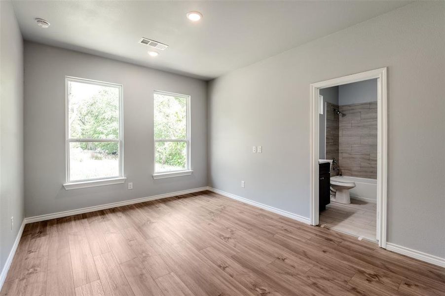 Unfurnished bedroom with light hardwood / wood-style floors and ensuite bath