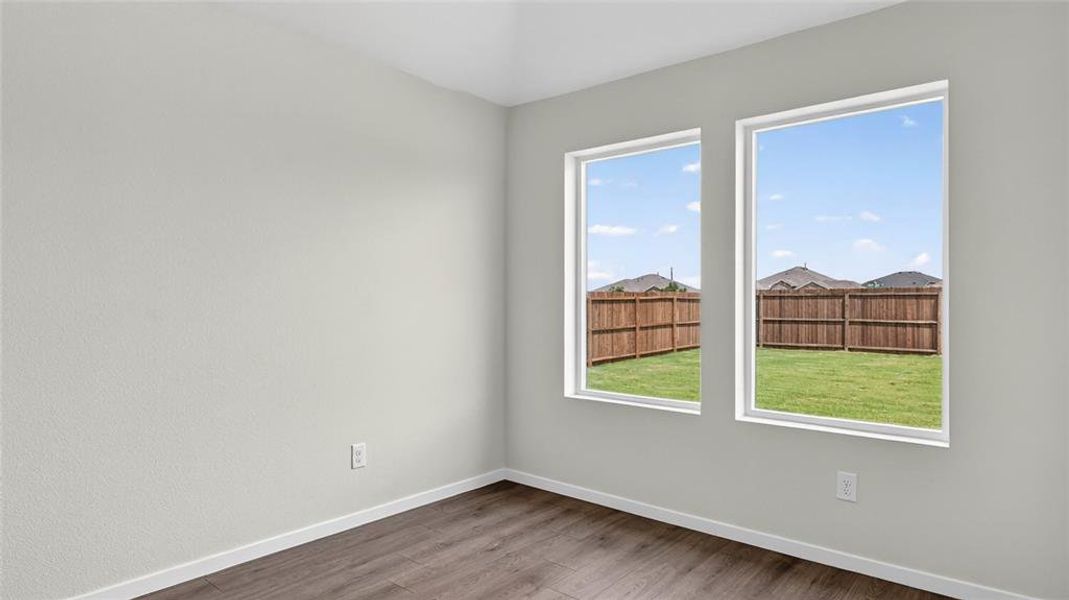 Room featuring two large windows, wood-finish flooring, and light-toned walls
